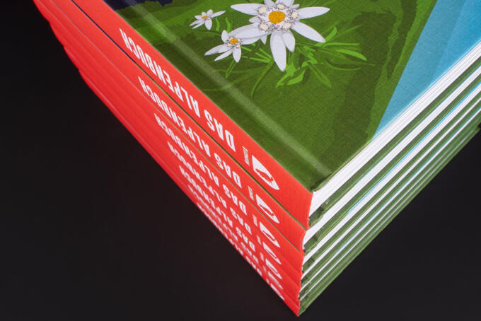 Hardcoverbuch über die Alpen gestapelt